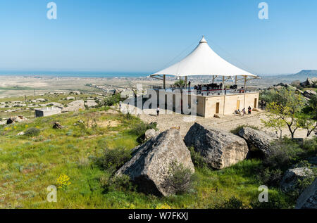 Gobustan, Azerbaigian - 1 maggio 2019. Paesaggio in Gobustan national park, con padiglione, di persone e di Gobustan insediamento nella distanza. Foto Stock