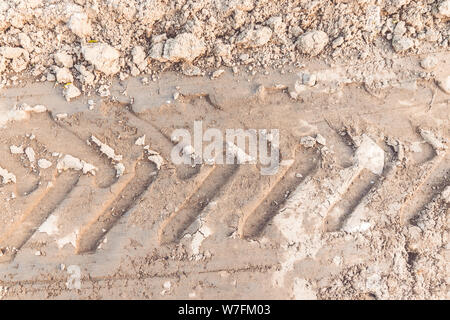 Traccia dei pneumatici su sterrato sabbia o fango, Picture rétro o tono di grunge. La strada via. Via da un pneumatico del trattore al suolo Foto Stock