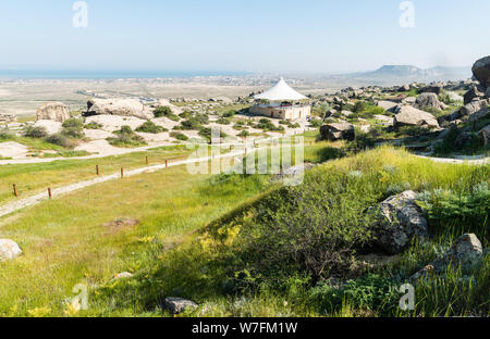 Gobustan, Azerbaigian - 1 maggio 2019. Paesaggio in Gobustan national park, con percorsi, Pavilion, di persone e di Gobustan insediamento nella distanza. Foto Stock