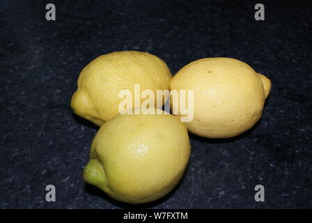 Più limoni al buio su un piano di lavoro della cucina. Foto Stock