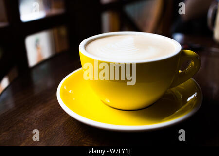 Giallo tazza di caffè aromatico su un tavolo di legno. Foto Stock
