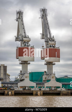 Dockside Gantry cranes è utilizzare in pontili accanto al fiume Garonne, Bordeaux, Francia. Pesanti gru di sollevamento entro l'industrial estate. Foto Stock