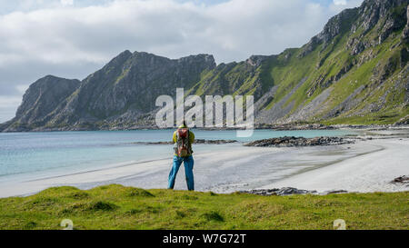 Uomo fotografo di viaggio blogger con fotocamera prendendo foto vista spiaggia Hoyvika in Norvegia, Isole Lofoten. Travel freelancer Foto Stock