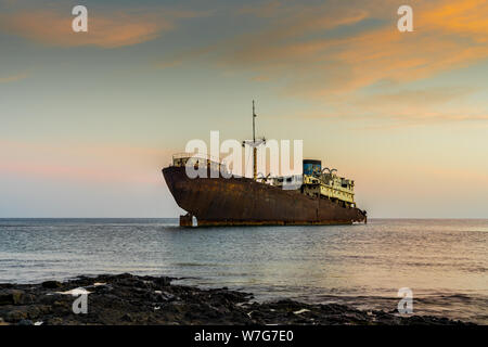 Spagna, Lanzarote, Temple hall barca relitto cordato a costa dell'isola nella magica luce post-incandescenza Foto Stock