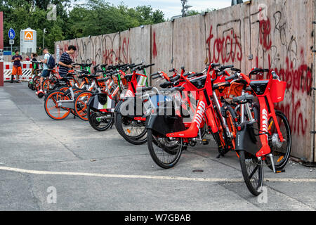 Elettrico a due ruote. E-scooter e batteria-powered biciclette disordine città marciapiedi fuori il palazzo della città nel quartiere Mitte di Berlino. Aziende rivali competere per lo spazio sui marciapiedi della città Foto Stock