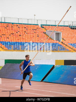 Pole Vault - un giovane uomo corre fino tenendo un palo Foto Stock