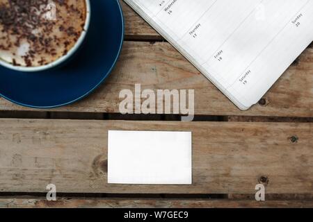 Foto di un gustoso cappuccino accanto a una penna e un libro di testo Foto Stock