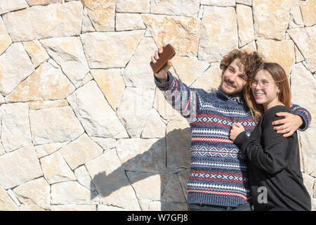 Giovani felici e sorridente giovane prendendo un selfie sui loro smartphone durante le proprie vacanze Foto Stock