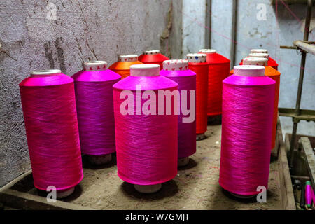 Rosa colorato bobine di filo per un telaio di tessitura attendono utilizzare, Varanasi, India Foto Stock