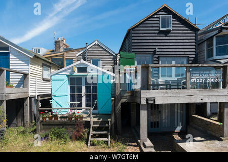 Weatherboard tradizionali case e capanne lungo la spiaggia a Whitstable, Kent, Regno Unito Foto Stock