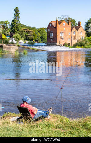 Sole di mattina su Cropthorne Mill e un pescatore accanto al fiume Avon a Fladbury, WORCESTERSHIRE REGNO UNITO Foto Stock