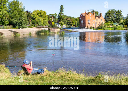 Sole di mattina su Cropthorne Mill e un pescatore accanto al fiume Avon a Fladbury, WORCESTERSHIRE REGNO UNITO Foto Stock