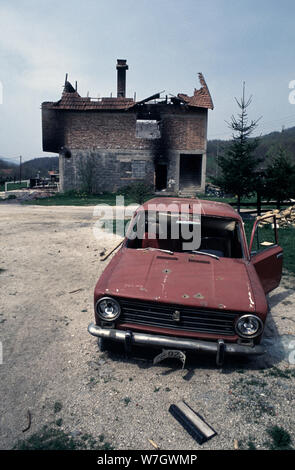 Il 26 aprile 1993 la pulizia etnica durante la guerra in Bosnia centrale: fori di proiettile in una vettura distrutto e un ristorante/caffetteria completamente distrutta da un incendio in background. Questo è lungo la strada tra Busovača e Medovici, attaccato da HVO (croato-bosniaci forze) dieci giorni prima. Foto Stock