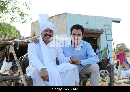 Rural man with his son sitting on cot Stock Photo