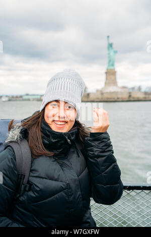 Ritratto di una bella donna che viaggiano in posa con la Statua della Libertà - immagine verticale Foto Stock