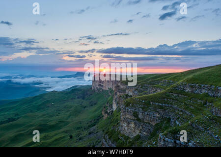 Tramonto in montagna. Il sole che illumina la gamma della montagna, nebbia e nuvole. Foto Stock