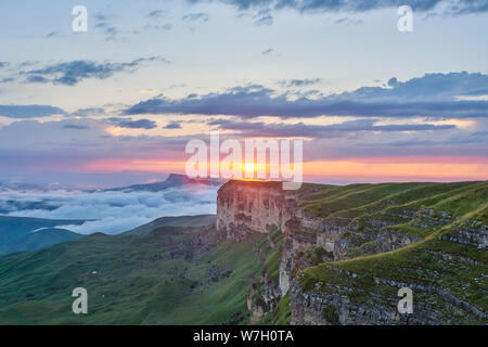 Tramonto in montagna. Il sole che illumina la gamma della montagna, nebbia e nuvole. Foto Stock