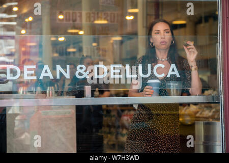 Una donna ha il caffè nella finestra del Dean & DeLuca store di Soho a New York Sabato, 3 agosto 2019. Di fronte alla concorrenza di una miriade di altre fonti il trail-blazing Dean & DeLuca ha accumulato un numero di fatture non pagate e non viene fornito da alcuni dei suoi fornitori. (© Richard B. Levine) Foto Stock