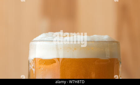 Testa di birra o collare di schiuma di gomma espansa sulla parte superiore della bevanda servita nel tradizionale tazza di vetro. Foto Stock