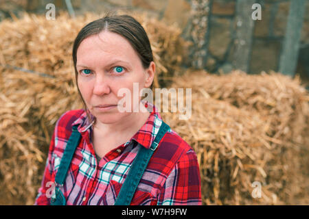 Ritratto di grave agricoltore femmina nella parte anteriore del pagliaio in agriturismo backyard Foto Stock