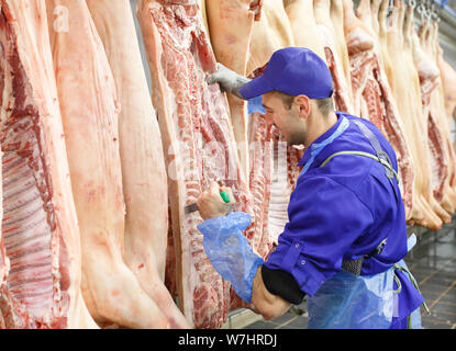 Butcher il taglio di carne di maiale alla produzione di carne Foto Stock