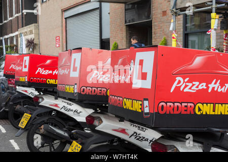 Una fila di Pizza Hut scooter parcheggiato al di fuori di uno dei suoi negozi su Fulham Road, Fulham, Londra, Regno Unito Foto Stock