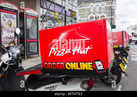 Una fila di Pizza Hut scooter parcheggiato al di fuori di uno dei suoi negozi su Fulham Road, Fulham, Londra, Regno Unito Foto Stock