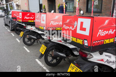 Una fila di Pizza Hut scooter parcheggiato al di fuori di uno dei suoi negozi su Fulham Road, Fulham, Londra, Regno Unito Foto Stock