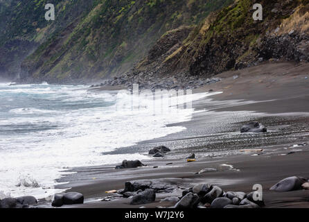 Le onde del mare gli schizzi sulla spiaggia bagnata nei pressi di ripide scogliere, nelle Azzorre, Portogallo. Foto Stock
