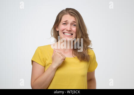 Donna sensazione scomoda, guardando con uno strano sorriso dopo aver fatto errori e di essere colpevole Foto Stock