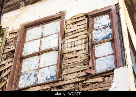 Le finestre sono dipinti di bianco. Le pareti della casa sono molto distrutto dalla vecchiaia. La casa non è più adatto per vivere. Foto Stock