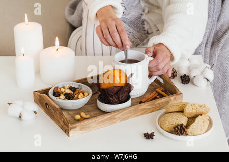 Ragazza bevande calde tè con biscotti, dadi, tortina Foto Stock