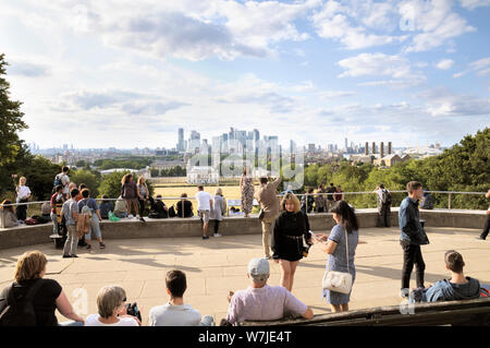 Turisti in un famoso punto panoramico che si affaccia su Greenwich Park e sull'Old Royal Naval College che guardano verso il quartiere finanziario di Canary Wharf, Londra, Regno Unito Foto Stock