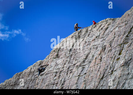 Gli alpinisti salire una verticale Parete di roccia utilizzando corde, i cavi elettrici e la specialità in un week-end in una valle di montagna Foto Stock