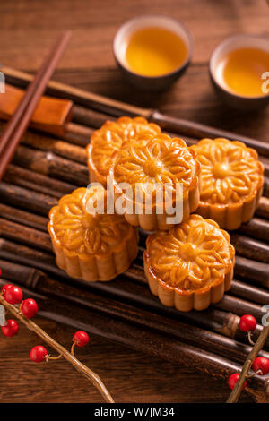 Cinese tradizionale pasticceria dolce della luna Mooncake con tazze tè sul bambù vassoio servingwarning su sfondo di legno per Mid-Autumn Festival, vicino. Foto Stock