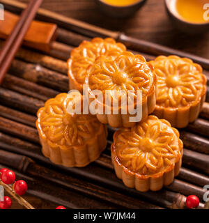 Cinese tradizionale pasticceria dolce della luna Mooncake con tazze tè sul bambù vassoio servingwarning su sfondo di legno per Mid-Autumn Festival, vicino. Foto Stock