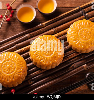 Cinese tradizionale pasticceria dolce della luna Mooncake con tazze tè sul bambù vassoio servingwarning su sfondo di legno per Mid-Autumn Festival, vicino. Foto Stock