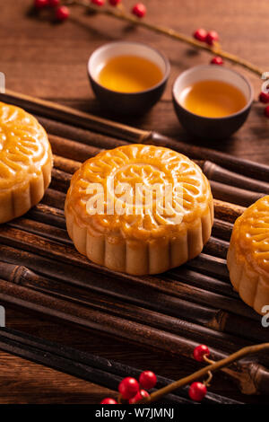 Cinese tradizionale pasticceria dolce della luna Mooncake con tazze tè sul bambù vassoio servingwarning su sfondo di legno per Mid-Autumn Festival, vicino. Foto Stock