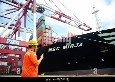 --FILE--un lavoratore cinese dirige un veicolo di gru per il sollevamento contrainers per essere spediti all'estero da parte dei camion su una banchina del porto di Qingdao nella città di Qingdao Foto Stock