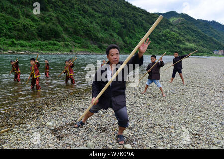 I bambini cinesi di Miao gruppo etnico che indossano costumi tradizionali pratica ''Miao stickfighting'', una singolare arte marziale del Miao Arti Marziali unde Foto Stock