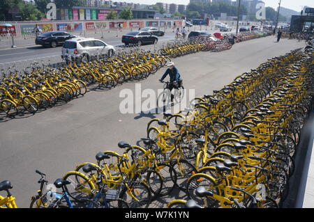 --FILE--un ciclista passa di biciclette di Mobike (arancione), ofo (giallo) e altri cinesi bike-servizi di condivisione su una strada a Pechino in Cina, 19 giugno Foto Stock