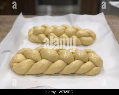 Supporto challah in casa pane di pasta intrecciata prima della sua cotta su una carta di rinforzo Foto Stock