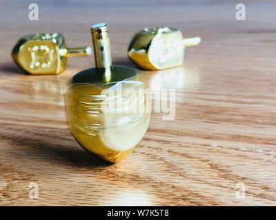 Oro filatura Dreidel alto su un pavimento di legno Hanukkah giocattolo tradizionale festa ebraica Foto Stock