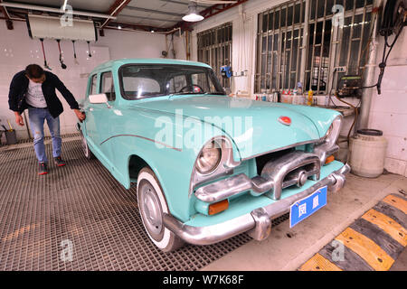 Il proprietario del 59-anno-vecchio 'Phoenix' auto d'epoca, pulisce la berlina dopo due mesi di lavori di ristrutturazione presso un garage in Cina a Shanghai, 28 settembre 2017. Foto Stock