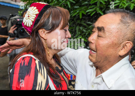 Il 33-anno-vecchio Genakuli Mahamat dal Xinjiang, abbracci la sua " padre " Li Zhongyi che ha aiutato il suo ritorno a casa dopo essere stata persa a Chengdu 21 anni fa Foto Stock