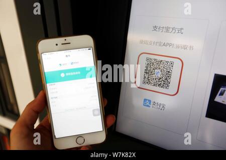 Un cittadino esegue la scansione di un codice QR tramite il servizio di pagamento mobile di Alipay Alibaba gruppo sul suo smartphone per prendere libri in prestito gratuitamente di fronte di una libreria condivisa Foto Stock