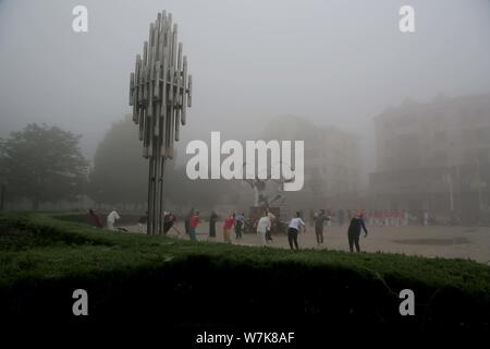 I residenti locali che indossano maschere viso contro l'inquinamento atmosferico hanno allenamento fisico nella fitta nebbia in città Lianyungang, est cinese della provincia di Jiangsu, 7 Sep Foto Stock