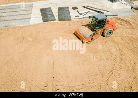 Rullo stradale prepara il terreno per la futura costruzione di strada. compattatore lavora sulla zona di sabbia Foto Stock