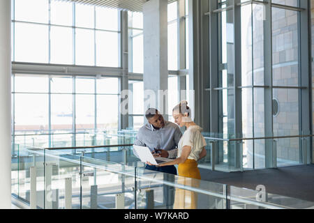 Due giovani uomini di affari che stare lavorando in ufficio moderno lobby Foto Stock