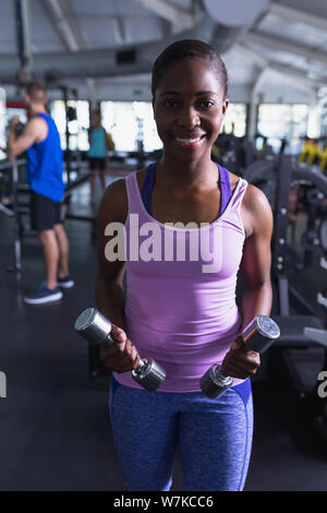 Montare donna esercizio con manubri in centro fitness Foto Stock